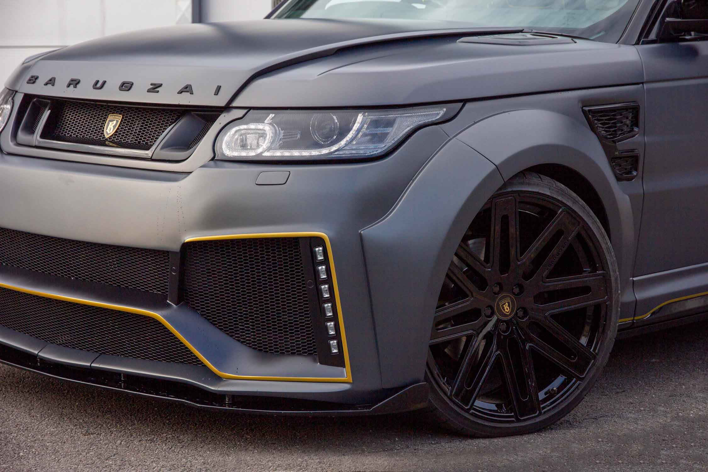 Range Rover Sport L494 fitted with Barugzai Cabaro bodykit with a prominent front detail shot on a tarmacked floor.