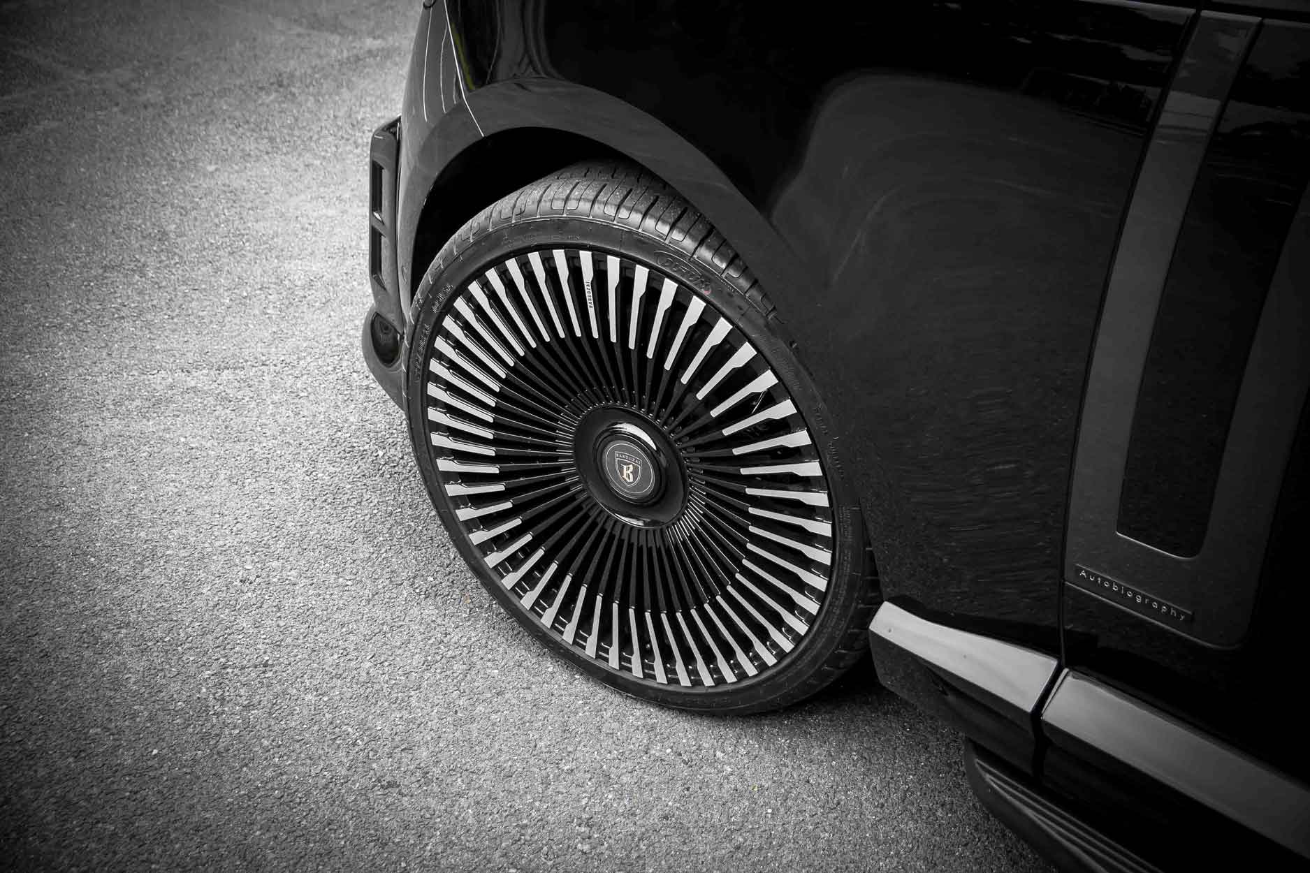 Close-up of a Range Rover L460 fitted with Barugzai Nebula bodykit, Vortex wheel with a distinctive rim design on a gray pavement.
