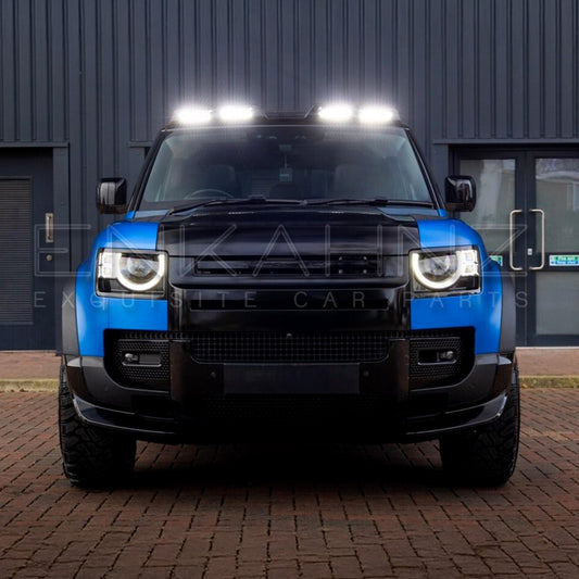 Blue SUV with additional lights on a brick driveway in front of a building.