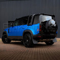 Load image into Gallery viewer, Blue SUV with black roof rack and spare tire cover on a brick surface.
