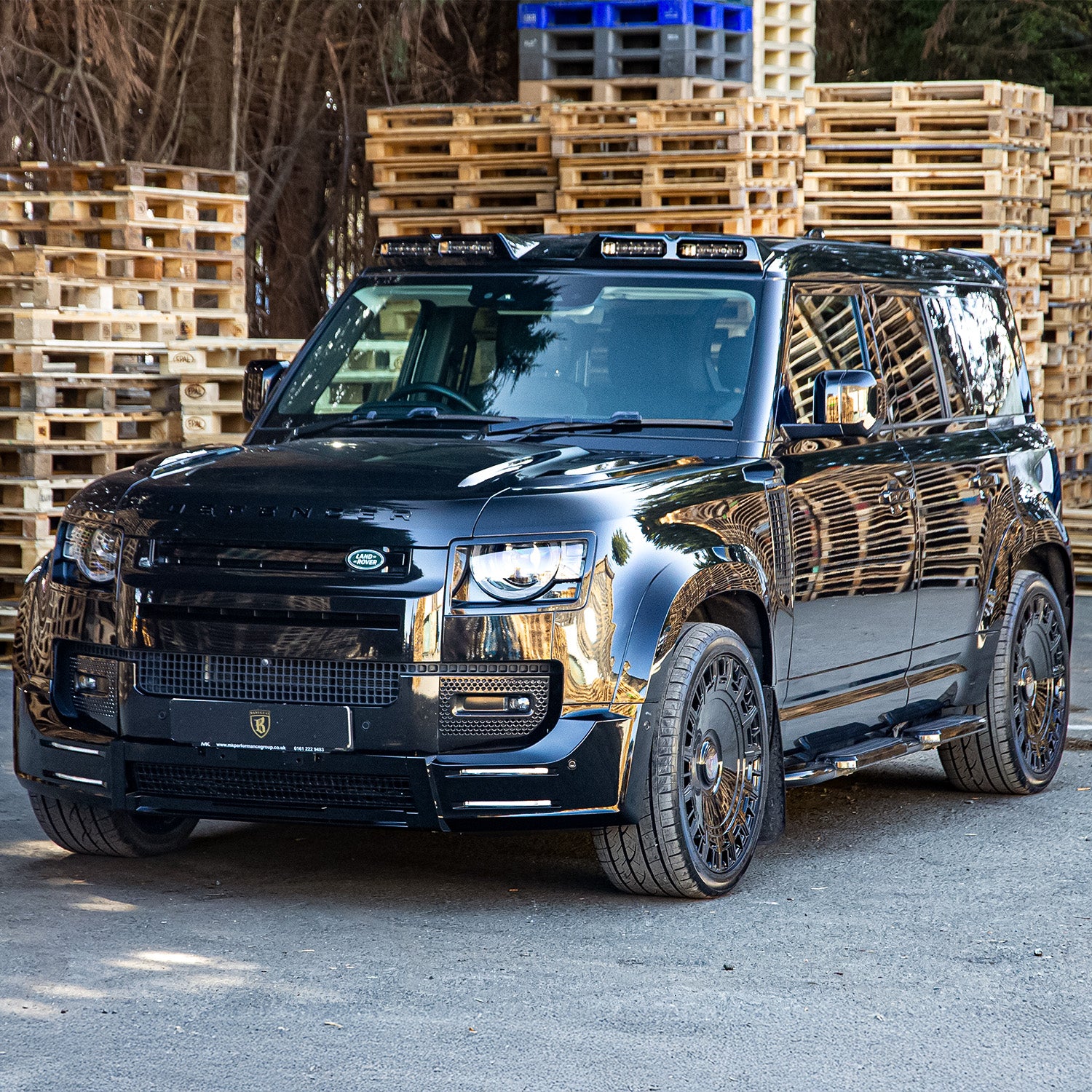Front quarter angle of Land Rover Defender showcasing Barugzai gloss black 22‑inch wheels and stance