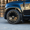 Load image into Gallery viewer, Front quarter close‑up zoom on Barugzai 22‑inch gloss black wheel and tyre detailing on Defender
