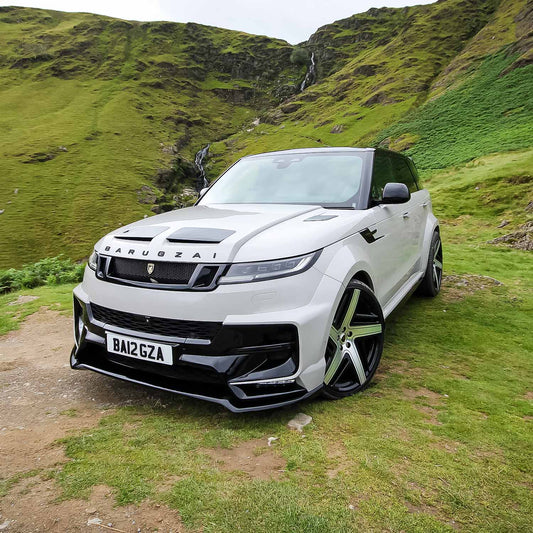 Front quarter angle of Range Rover Sport L461 with Barugzai Raptor bodykit, set against rolling green hills.