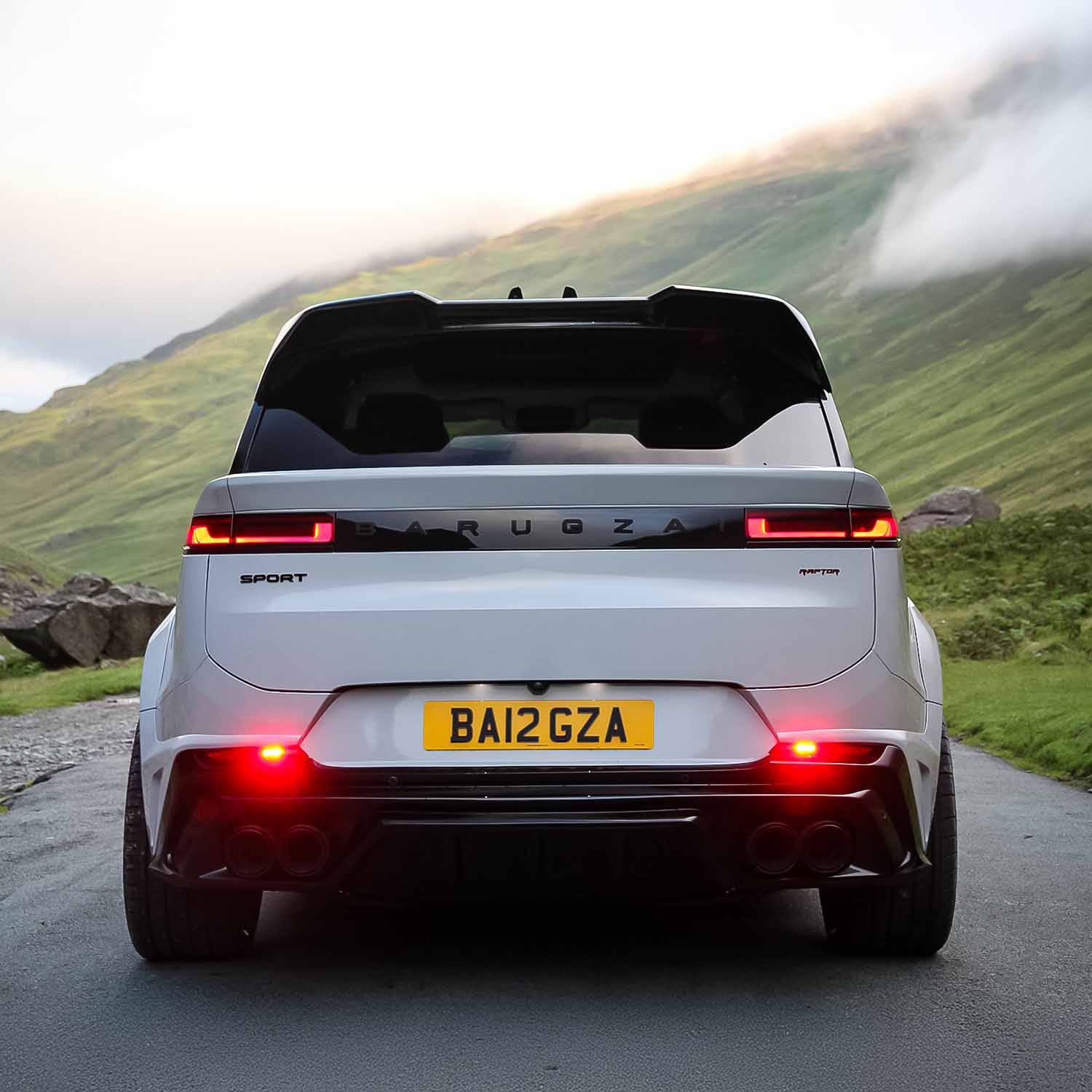 Rear angle of 2023 Range Rover Sport L461 on road with Barugzai Raptor bodykit, misty green hills in the background.