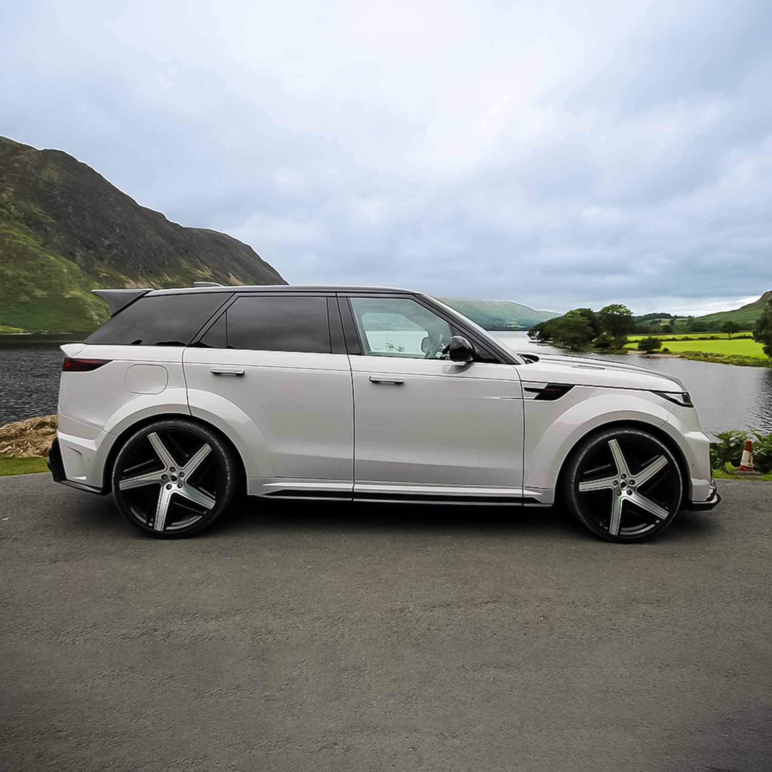 Side profile of Range Rover Sport L461 with Barugzai Raptor bodykit beside a lake and misty green hills.