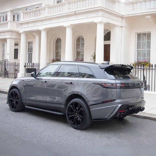 Rear quarter angle of Nardo Grey Velar Huntress parked near a white luxury hotel, showcasing bumper and diffuser styling.
