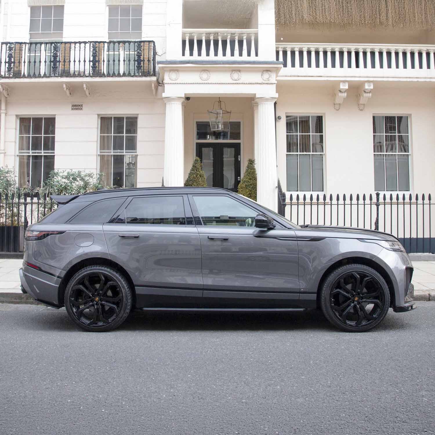 Side angle of Velar Huntress parked in front of hotel, emphasizing skirts and wheel fitment in Nardo Grey.