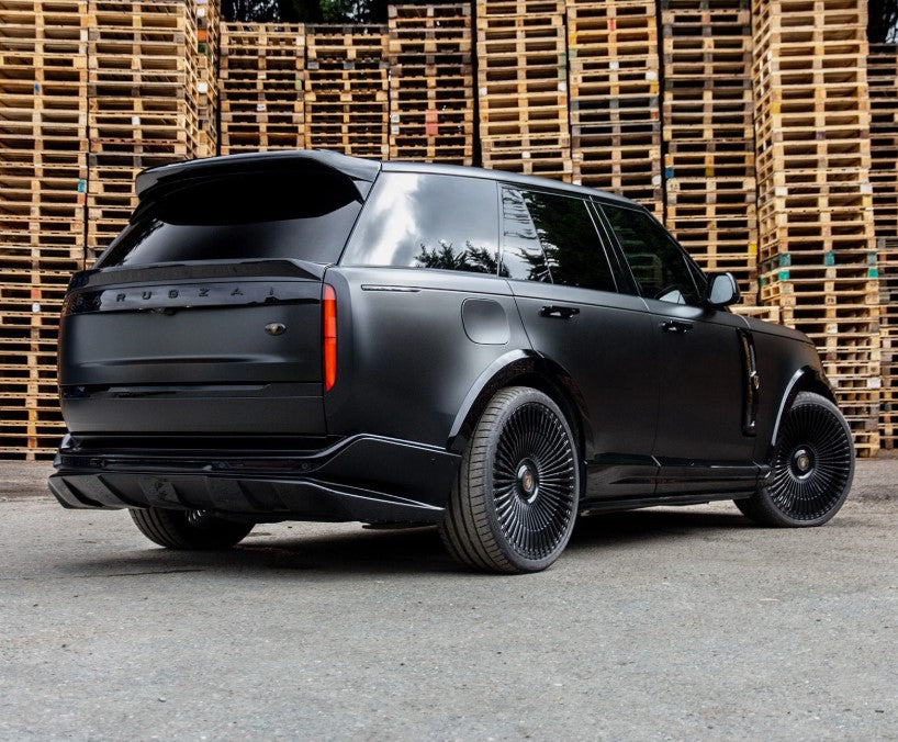 Rear quarter angle of Range Rover Vogue L460 2023+ with Barugzai Nebula bodykit, Vortex wheels, and contrasting black accents in a warehouse setting. 