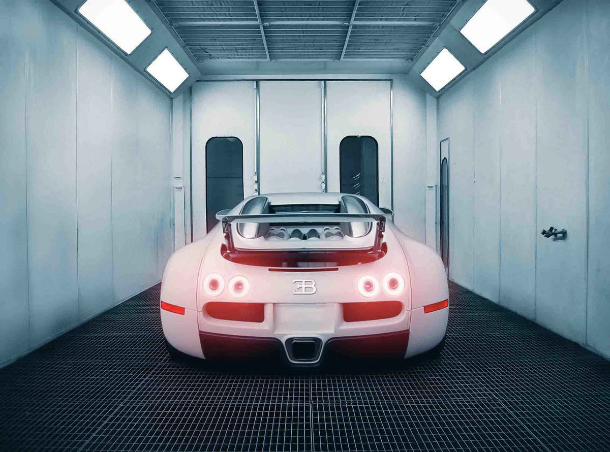 Back view of a White Bugatti Veyron car  with the rear lights on in the Enkahnz spray booth