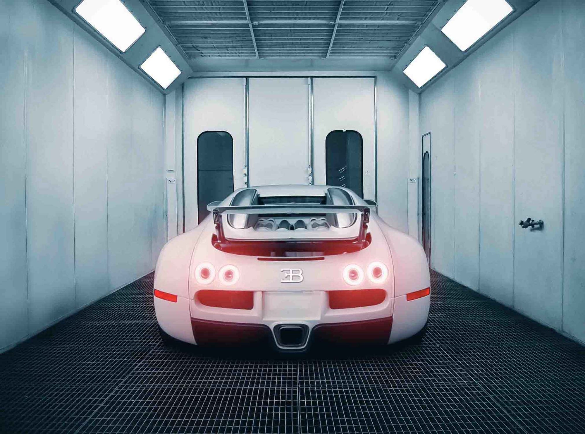 Back view of a White Bugatti Veyron car  with the rear lights on in the Enkahnz spray booth