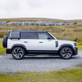 Load image into Gallery viewer, Side profile of the Defender 110 featuring the BARUGZAI Falcon bodykit, showcasing widened wheel arches, sporty side accents, and off-road capability.
