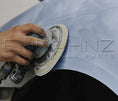 Load image into Gallery viewer, Close‑up of sanding disc in use on a car panel in bodyshop.
