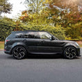 Load image into Gallery viewer, Side angle view of Range Rover Sport 2013-2017 with the LM Style bodykit from ENKAHNZ, emphasizing the sculpted side skirts and cohesive overall design in a natural park setting.
