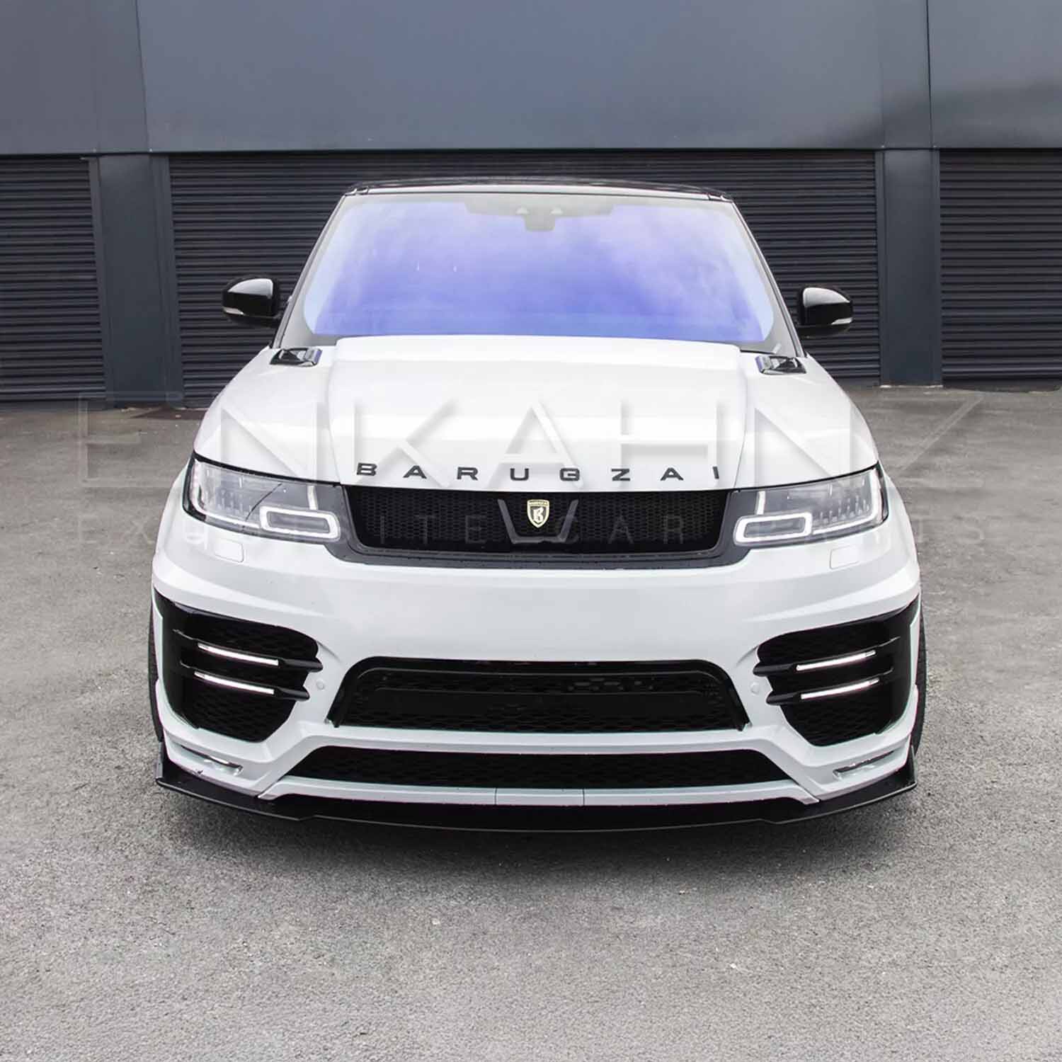 Close-up of a white Barugzai badge on a Range Rover Sport 2018–2022, with the Enkahnz LM style bodykit visible on a front-facing angle.