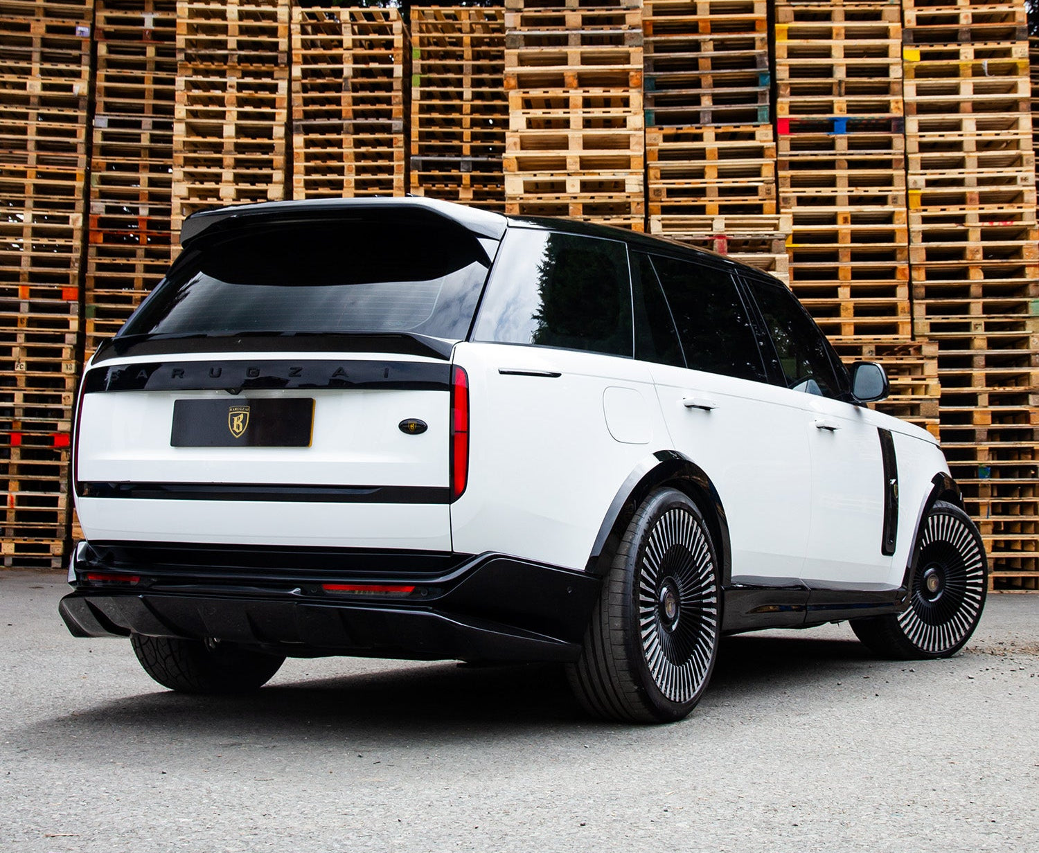 Rear Quarter View of a Gloss Black and White Range Rover Vogue L460 2022+ in a warehouse setting with Enkahnz Branding.