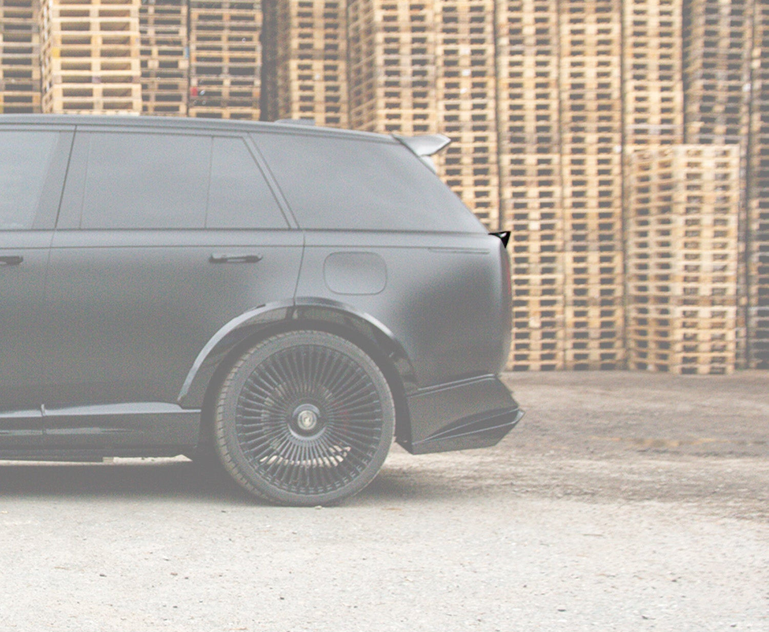 Side View of a Gloss Black Range Rover Vogue 2022+ L460 Mid Boot Spoiler in a warehouse setting with Enkahnz Branding.