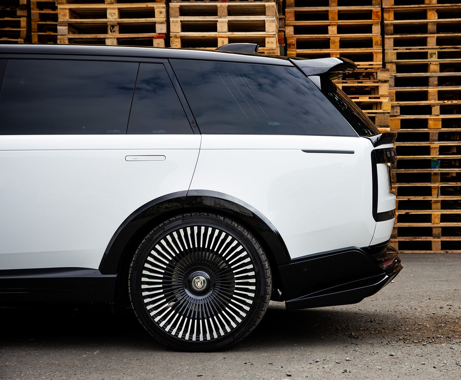 White Range Rover Vogue 2022+ closeup with a Roof Spoiler in front of wooden pallets, featuring Enkahnz branding.