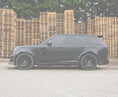 Load image into Gallery viewer, Side View of a Range Rover Vogue L460 2022+ Roof Spoiler on an opaque white background with the rest of the car in a warehouse setting.
