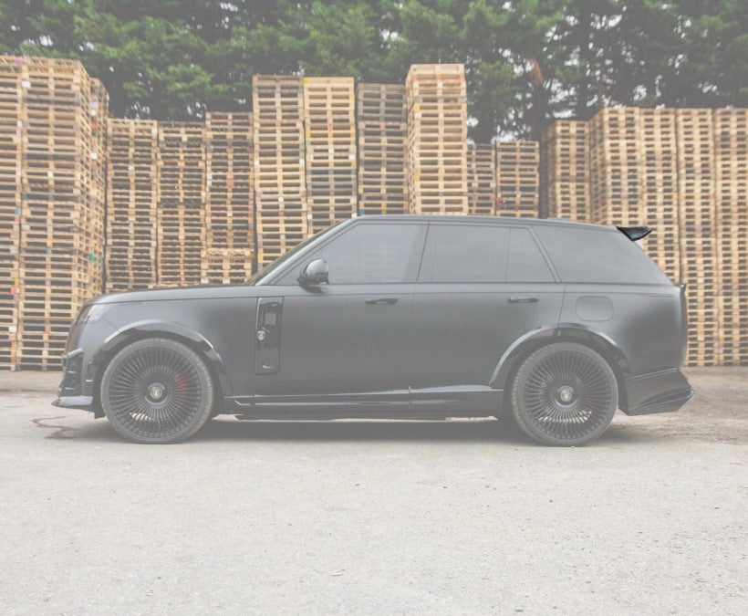 Side View of a Range Rover Vogue L460 2022+ Roof Spoiler on an opaque white background with the rest of the car in a warehouse setting.