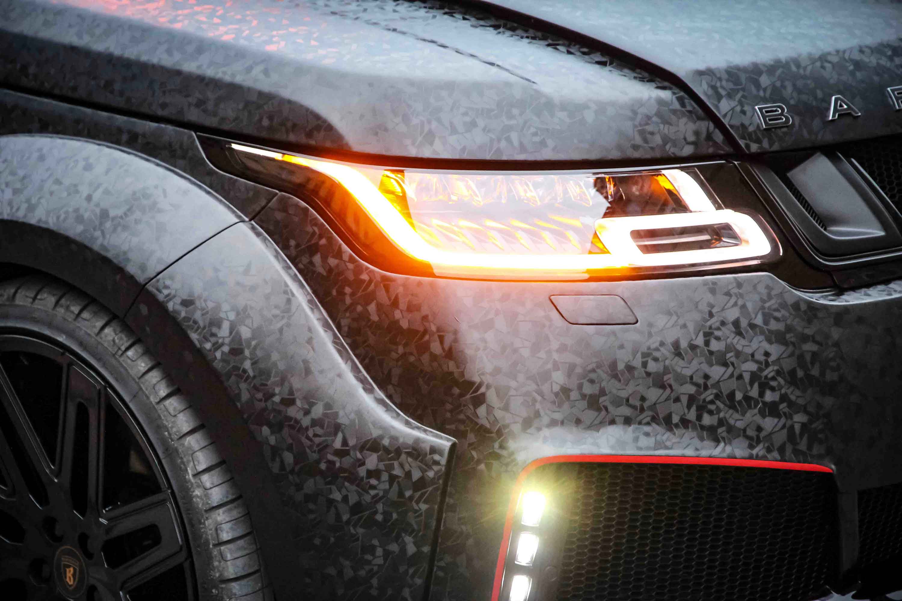 Close-up of a Range Rover Sport L494, fitted with Barugzai Cabaro II bodykit headlight with a blurred background