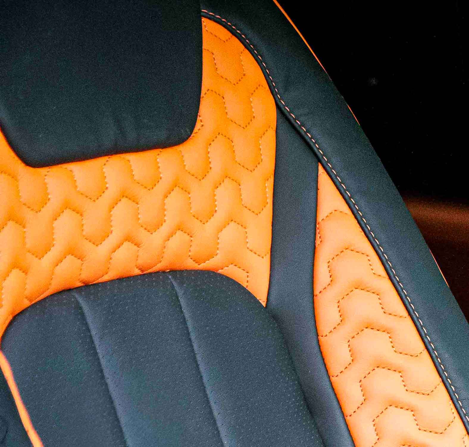 Close-up of a car seat with orange and black quilted design in a Land Rover Defender 110 L663