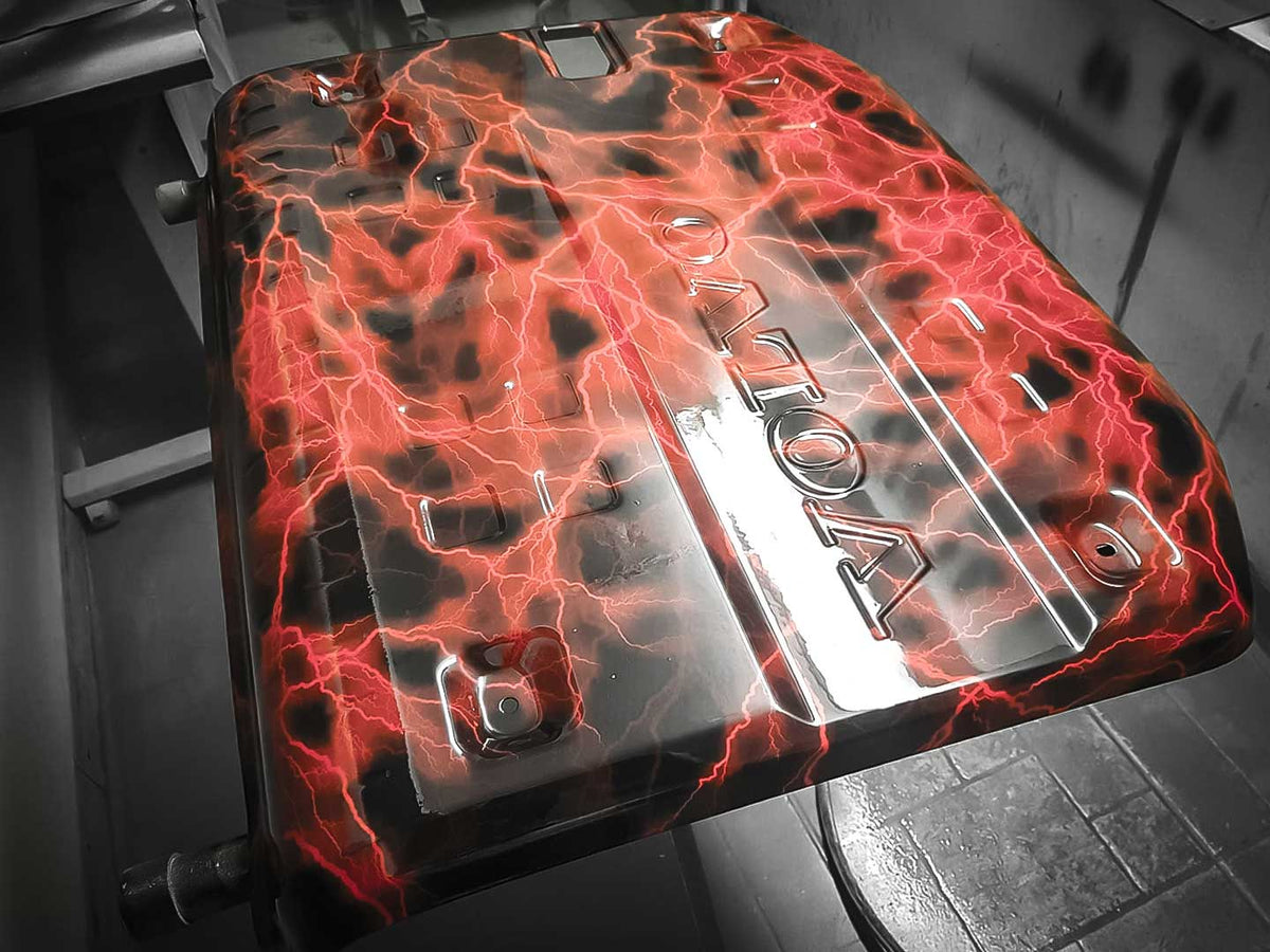 Metallic engine cover with red and black flame design hydro-dipped on a dark background