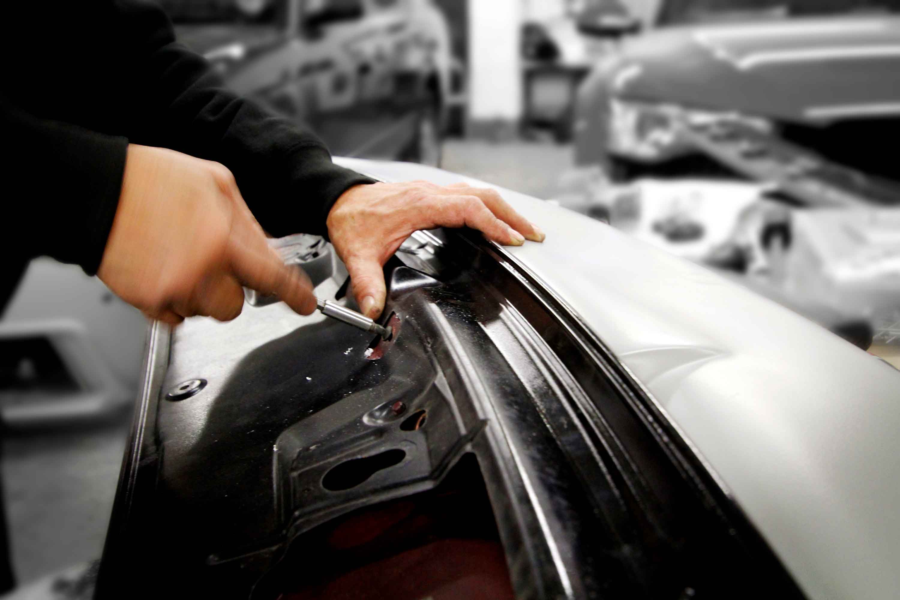 A worker fixing a diffuser trim on a rear bumper in the Enkahnz workshop 