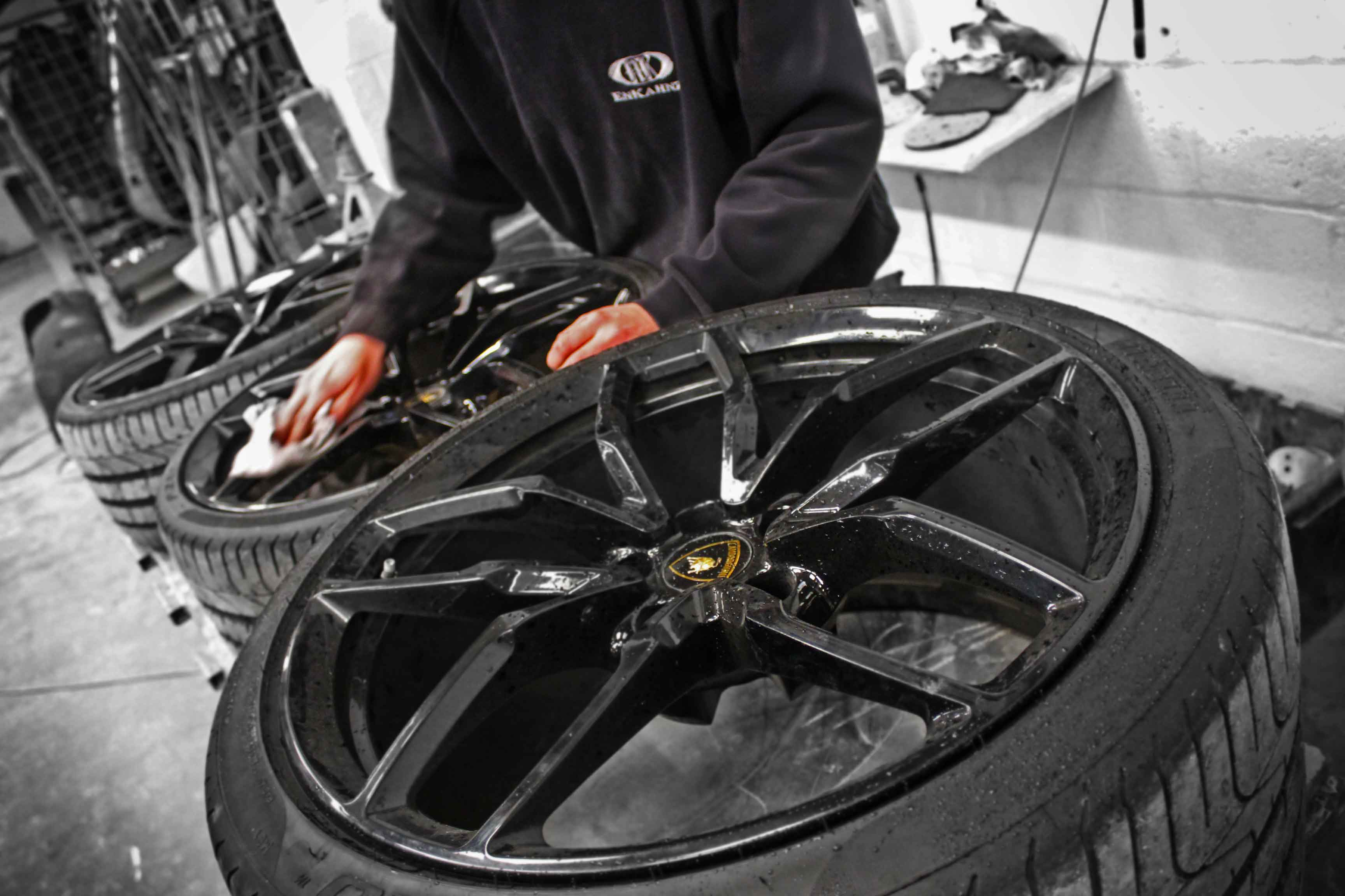Person cleaning a Lamborghini alloy wheel in the Enkahnz workshop 