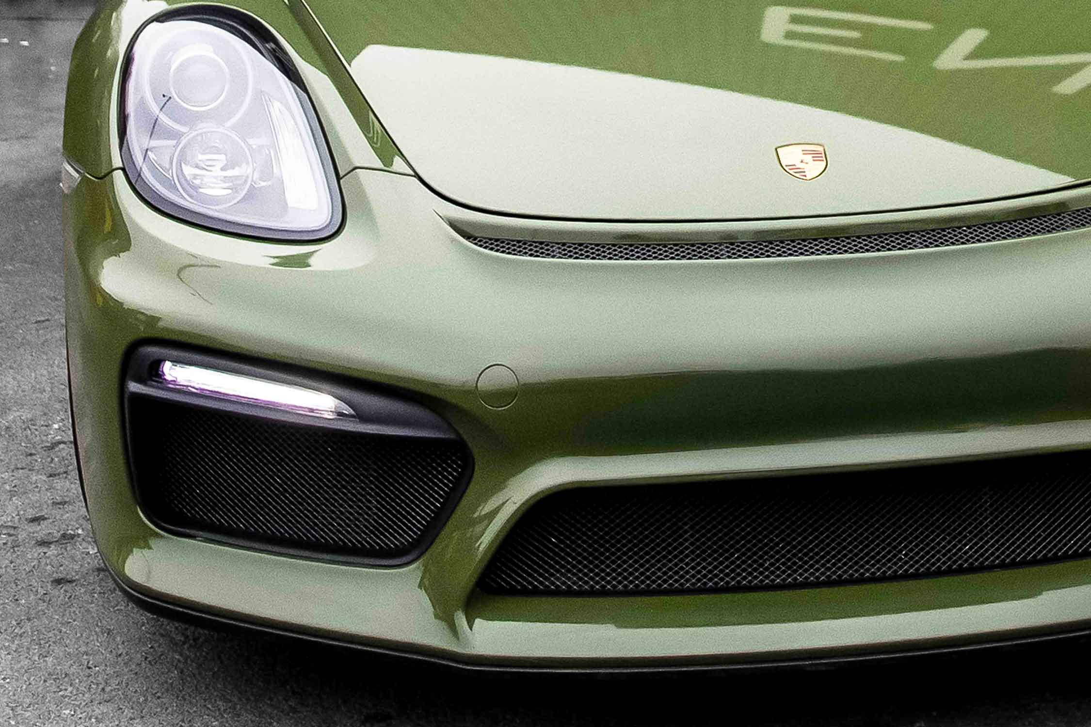 Close-up of a green Porsche 911 Spyder front grille and headlight, vinyl wrap in camo green 