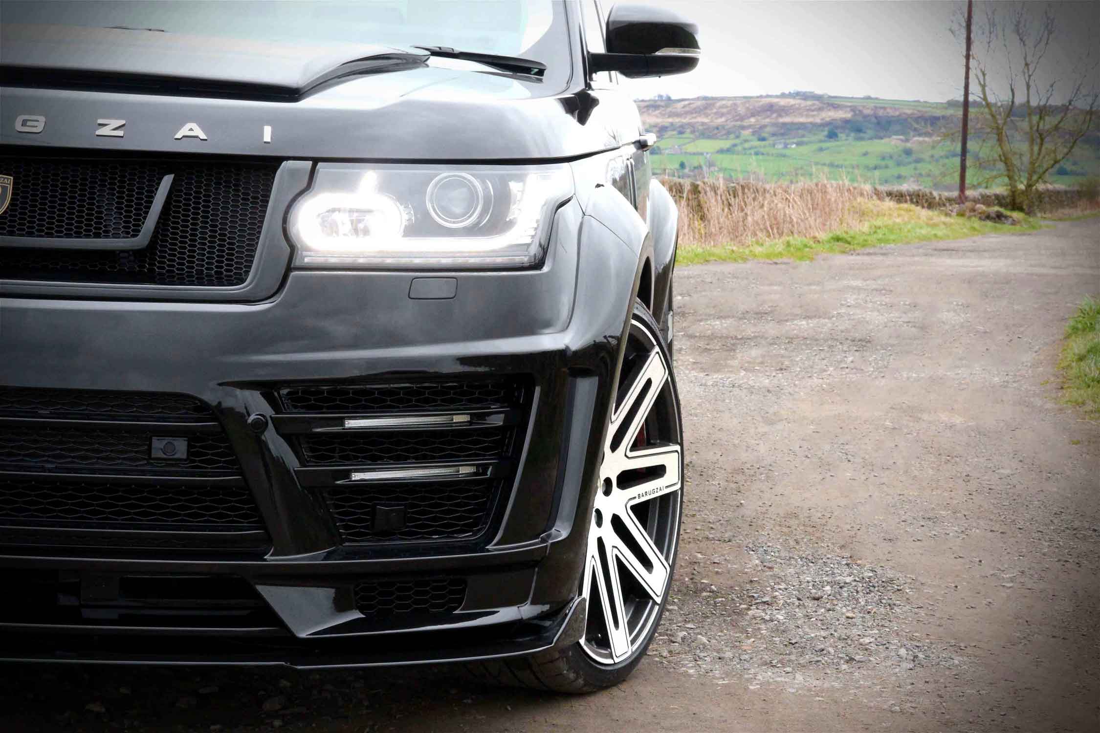 Close-up of a black Range Rover L405, fitted with the Barugzai Vogue Luxe bodykit on a road with a scenic background