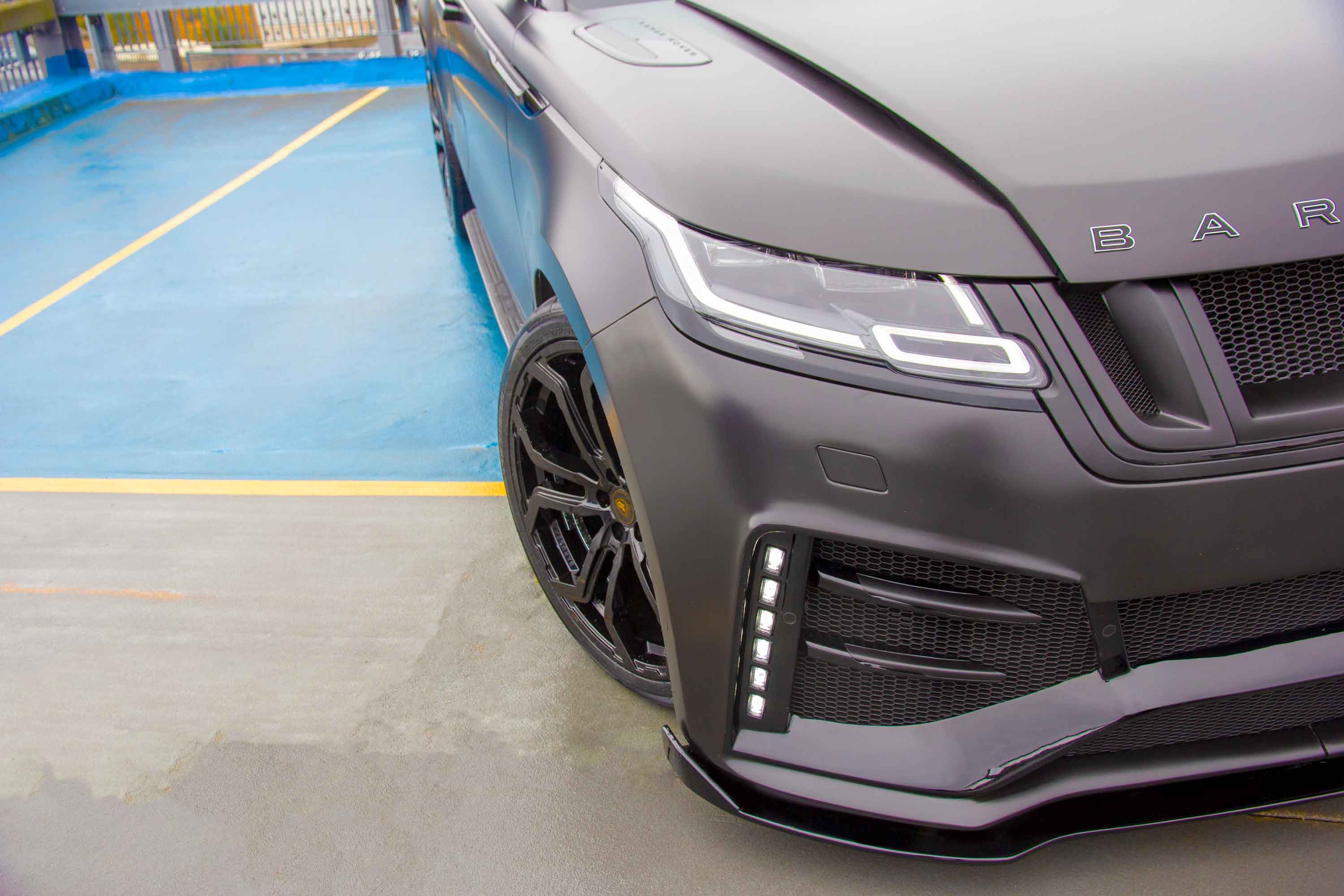 Close-up of a Range Rover Velar Barugzai Huntress front detail shot in a car park