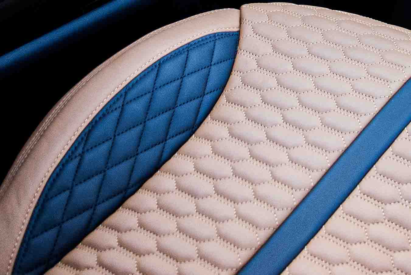 Close-up of a quilted  tanned leather seat with black accents on a dark background in a Range Rover Sport L494